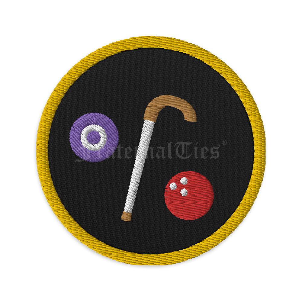A black circular Masonic patch with gold outline depicting two balls, one purple lawn ball and one red bowling ball; and a walking cane with brown handle.